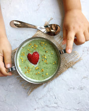Load image into Gallery viewer, Two toddler hands is holding a green smoothie bowl with strawberry served inside a Kiddobloom kids stainless steel bowl