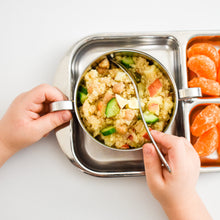 Load image into Gallery viewer, A kids holds a bowl by the handles to scoop couscous served inside a stainless steel bowl. The bowl is set on a stainless steel diivided plate. The small caviities have oranges.
