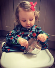 Load image into Gallery viewer, A baby girl is maneuvering her spoon scooping yogurt from a stainless steel bowl
